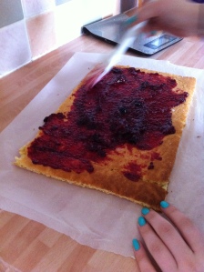 My daughter spreads the jam onto the top of her Swiss Roll.
